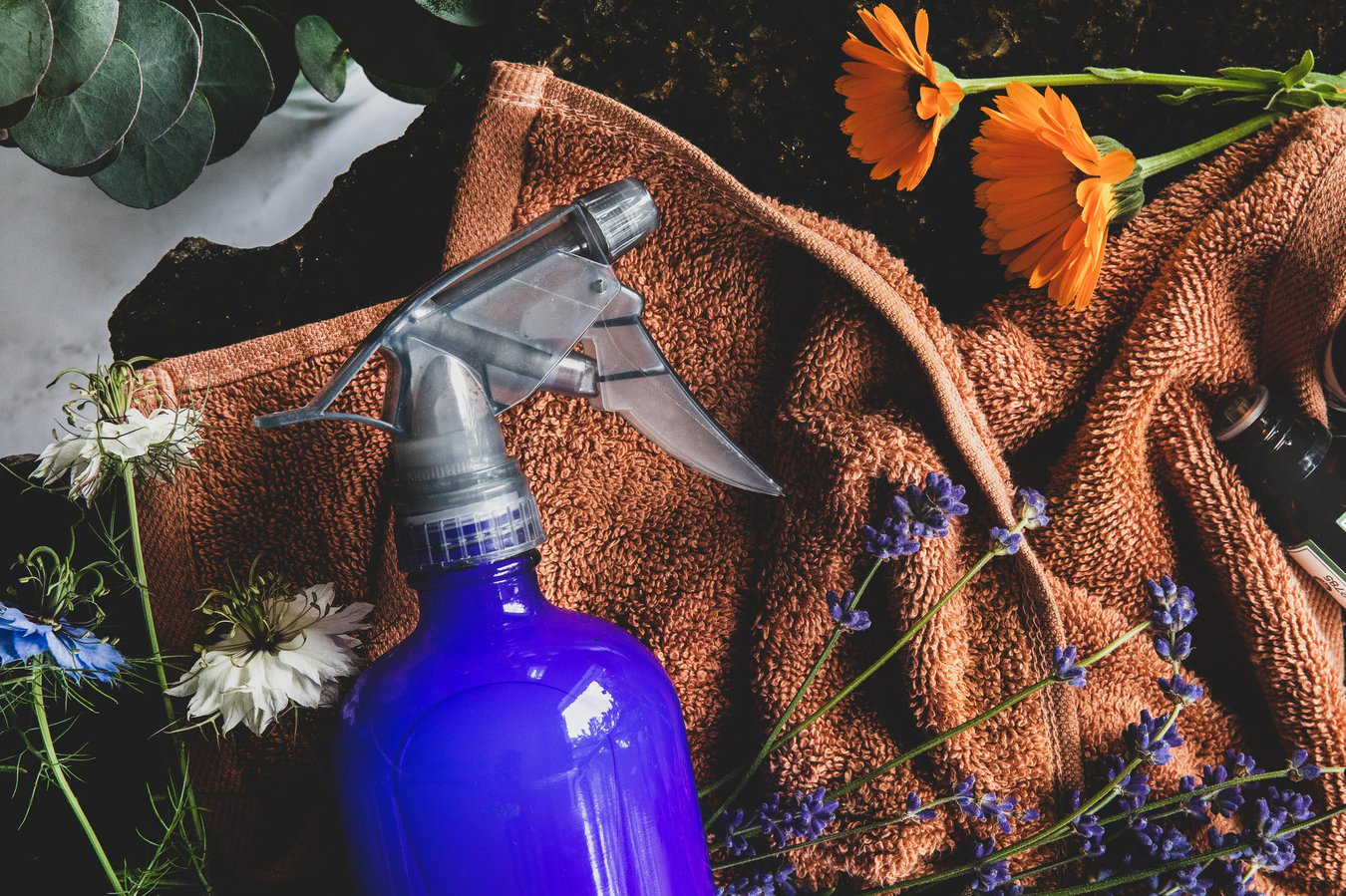 Spray bottle on a cloth with flowres and essential oils .