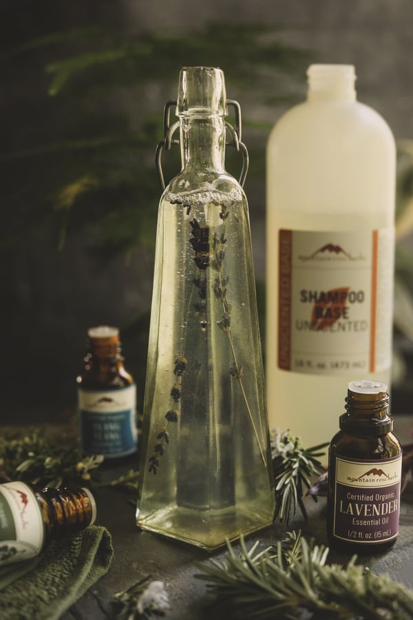 Beautiful glass jar with lavender suspended in liquid with bottles of essential oils. 