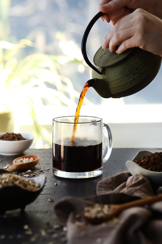 Dandelion root tea being poured from cast iron teapot.