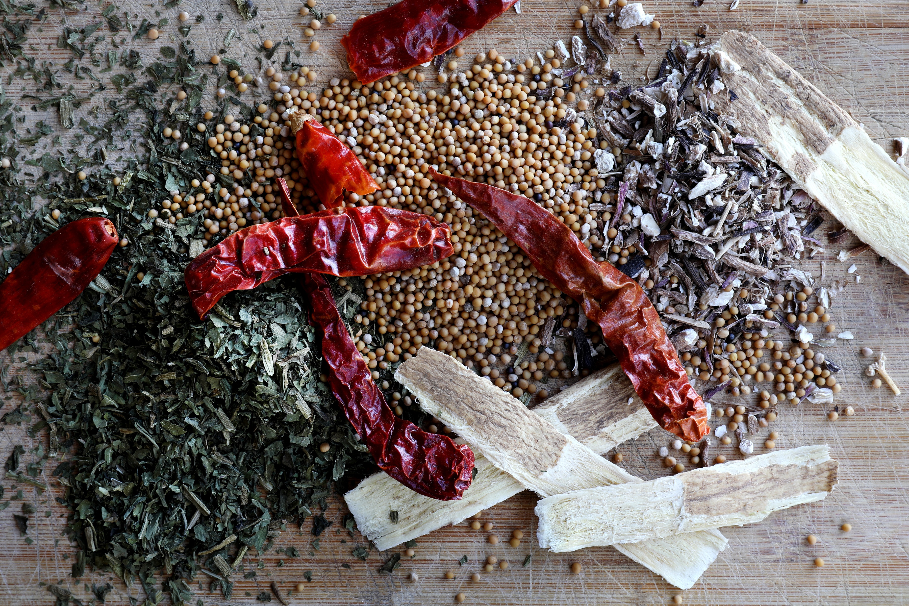 Vibrant colorful herbs, spices, and barks displayed on wood