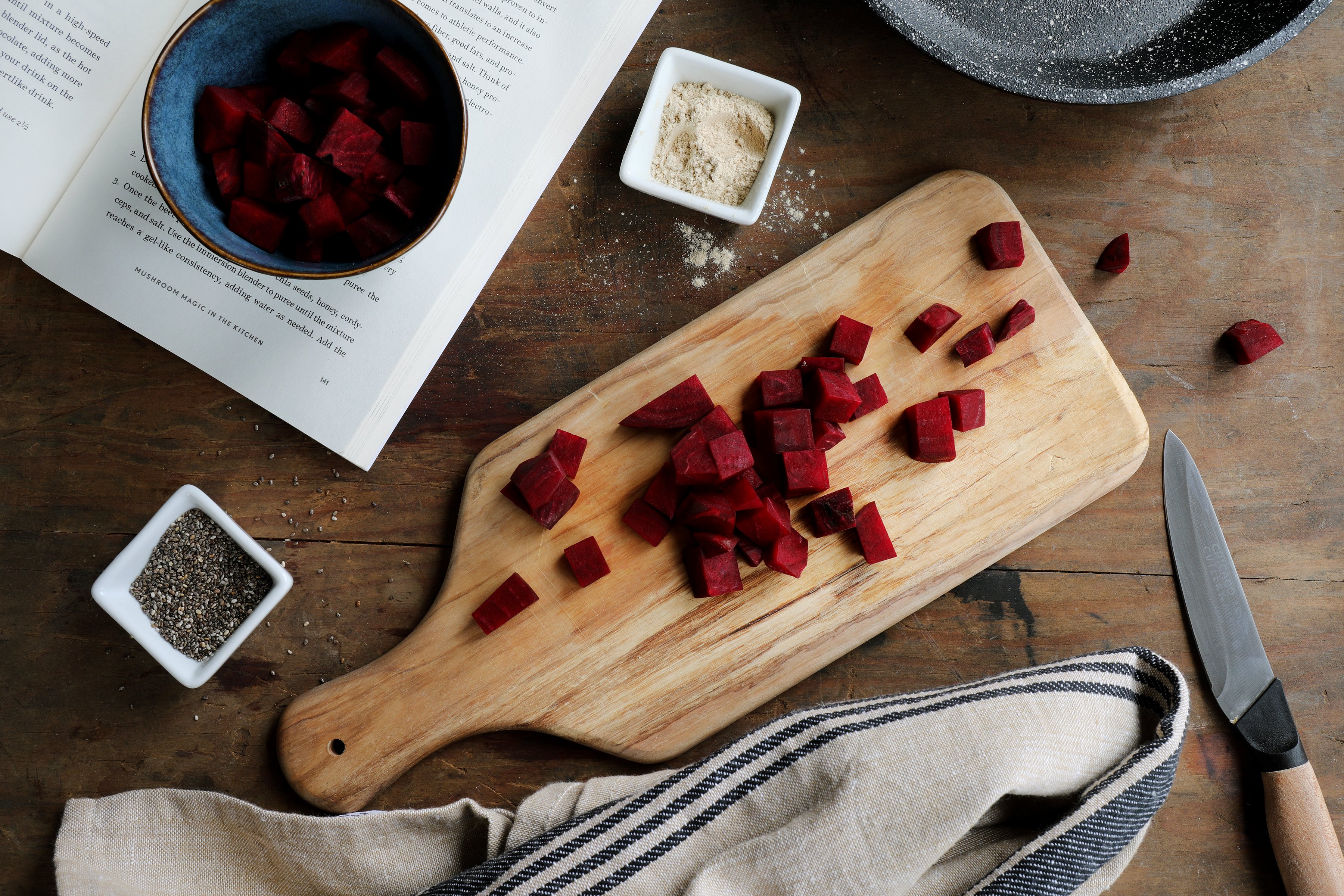 Cutting board with chopped beets with small bowls filled with other botanical ingredients. 