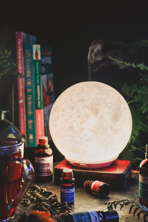Moon shaped essential oil diffuser with books and colorful essential oils. 