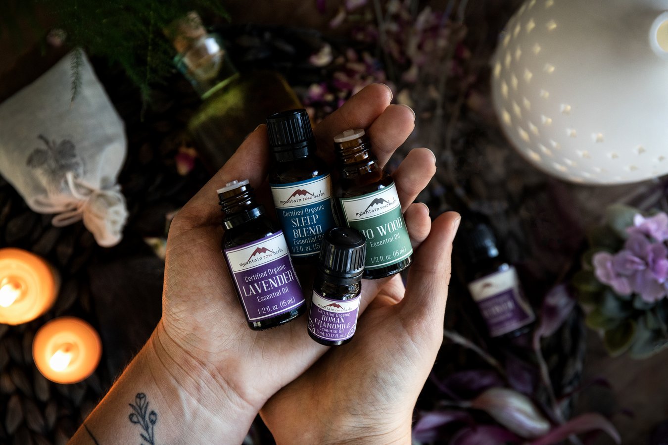 Hands holding ho wood, lavender, Roman chamomile, and Sleep Blend essential oils.