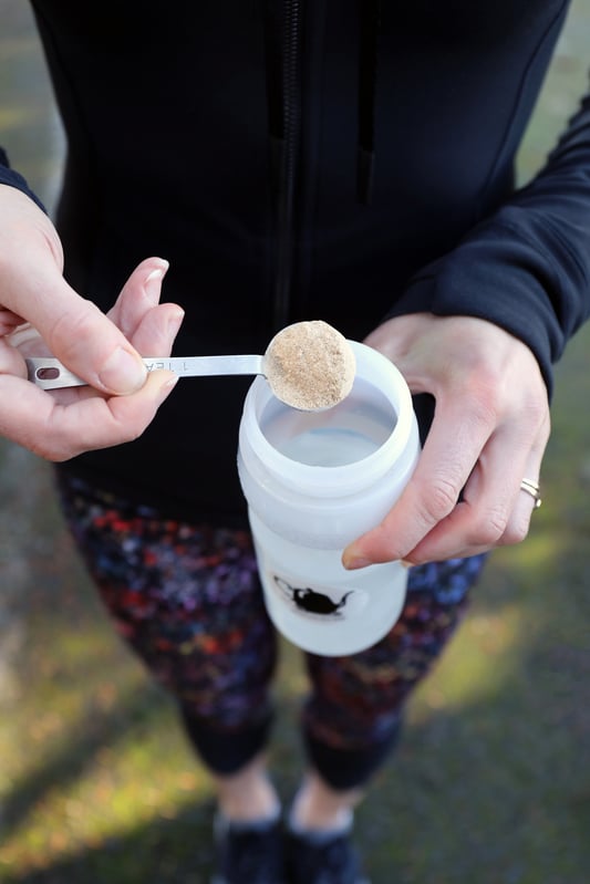 Woman pouring powder into sporty water bottle. 