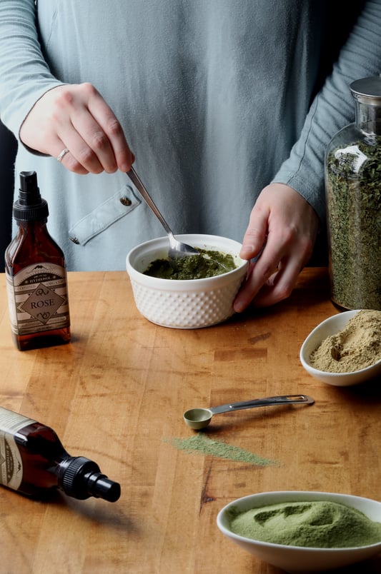 Hands mixing ayurvedic face mask from herbs and floral hydrosols