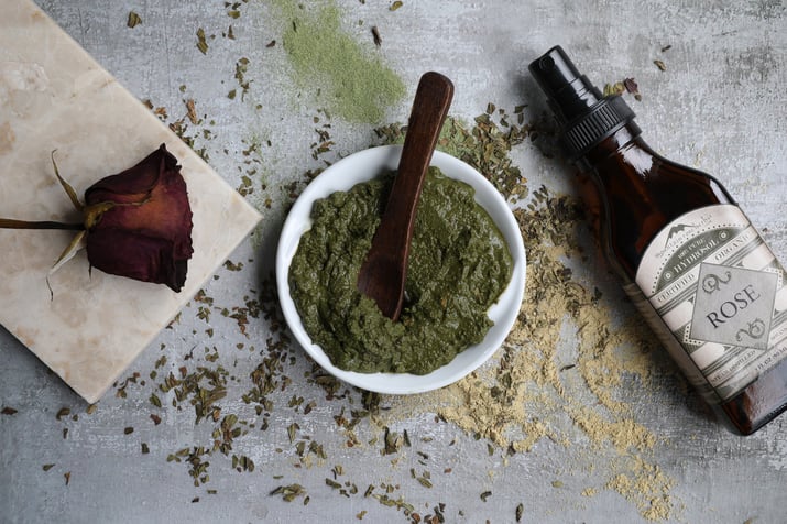 Wooden spoon mixing ayurvedic face mask with rose hydrosol and powders