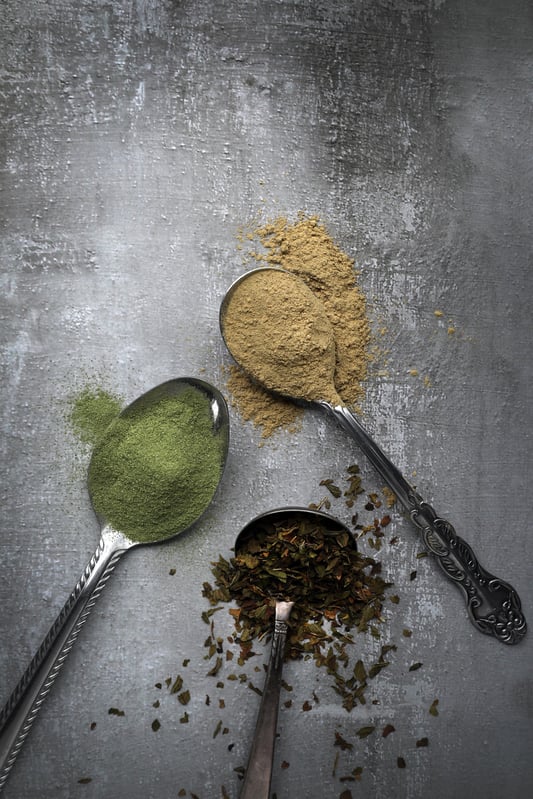 Three spoons laying out with ayurvedic herbs in them