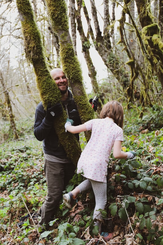 Father and daughter in forest playing and touching trees