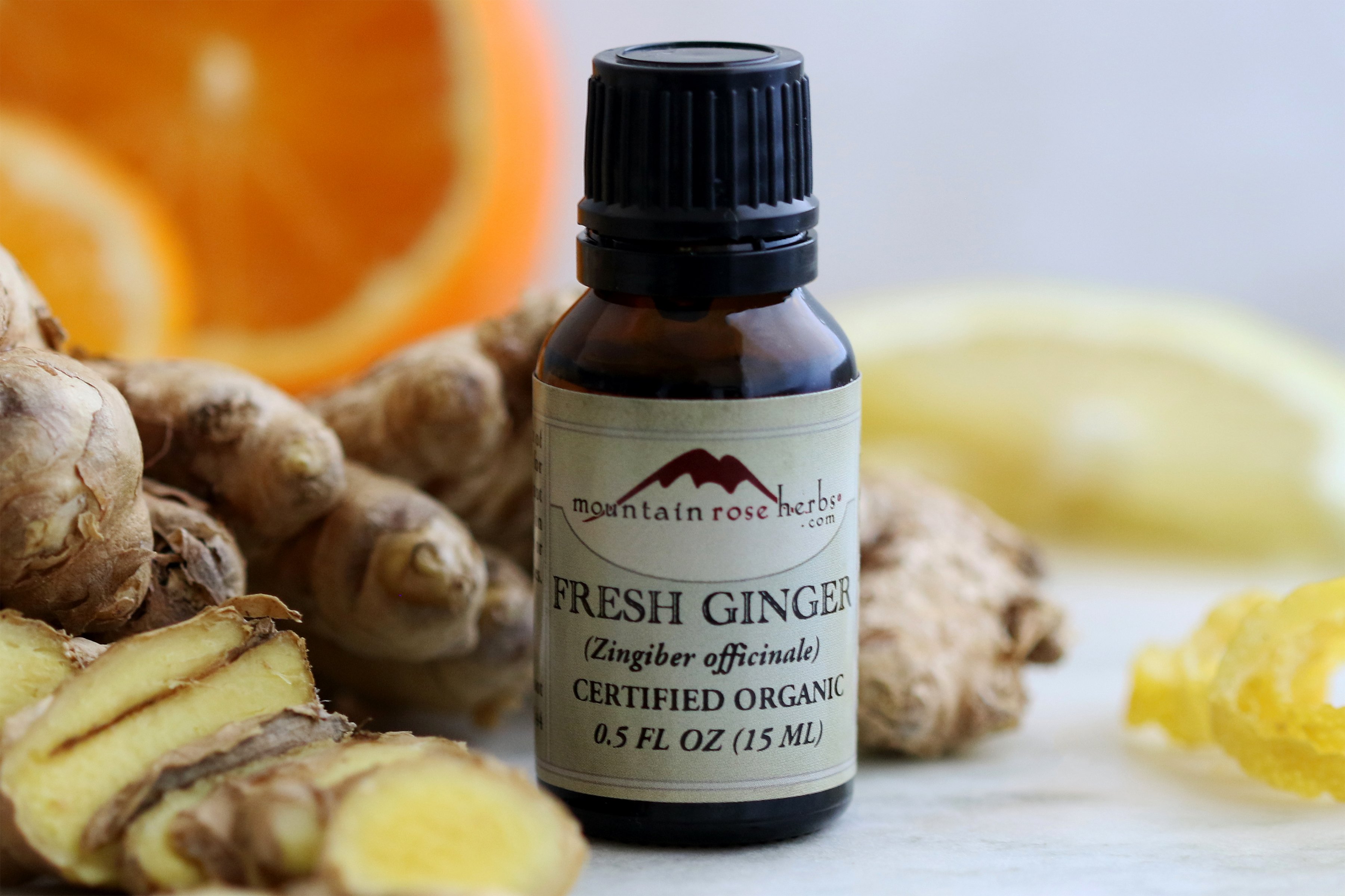 Organic fresh ginger essential oil arrange with fresh slices of ginger root, lemon, and orange. 