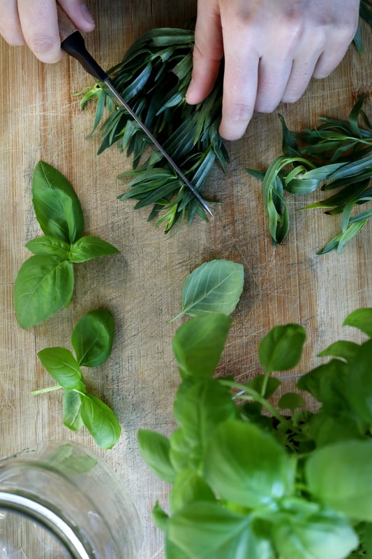 Hands chopping fresh vibrant herbs on wooden board