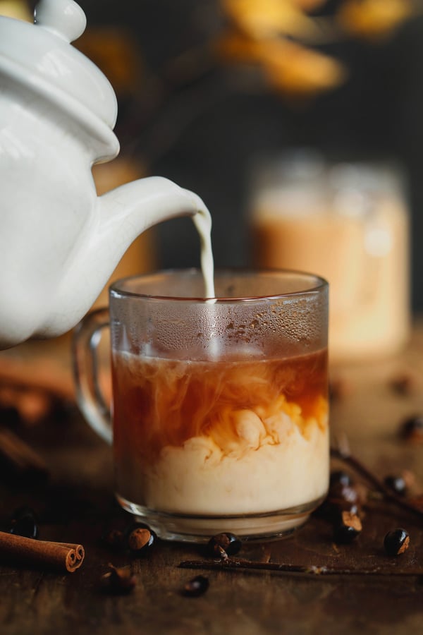 tea pot pouring milk into mug of tea