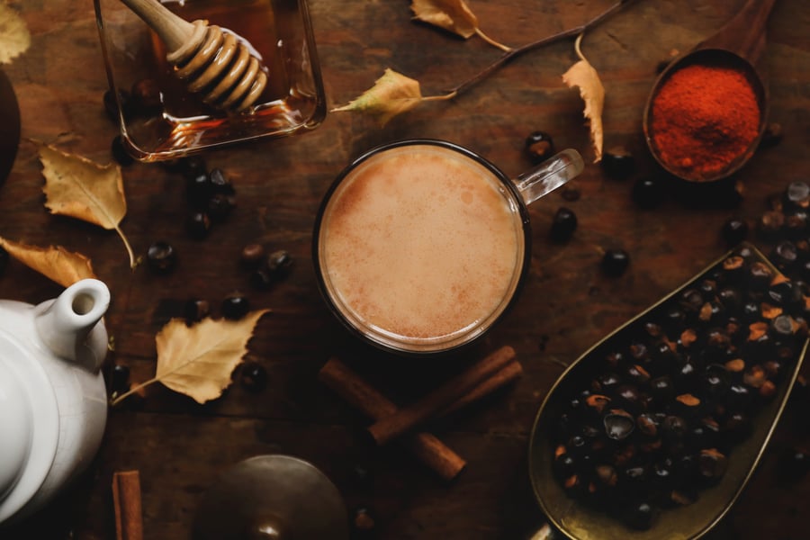 Gaurana seeds, mug with warm drink inside, tea pot, honey, cinnamon sticks on a table