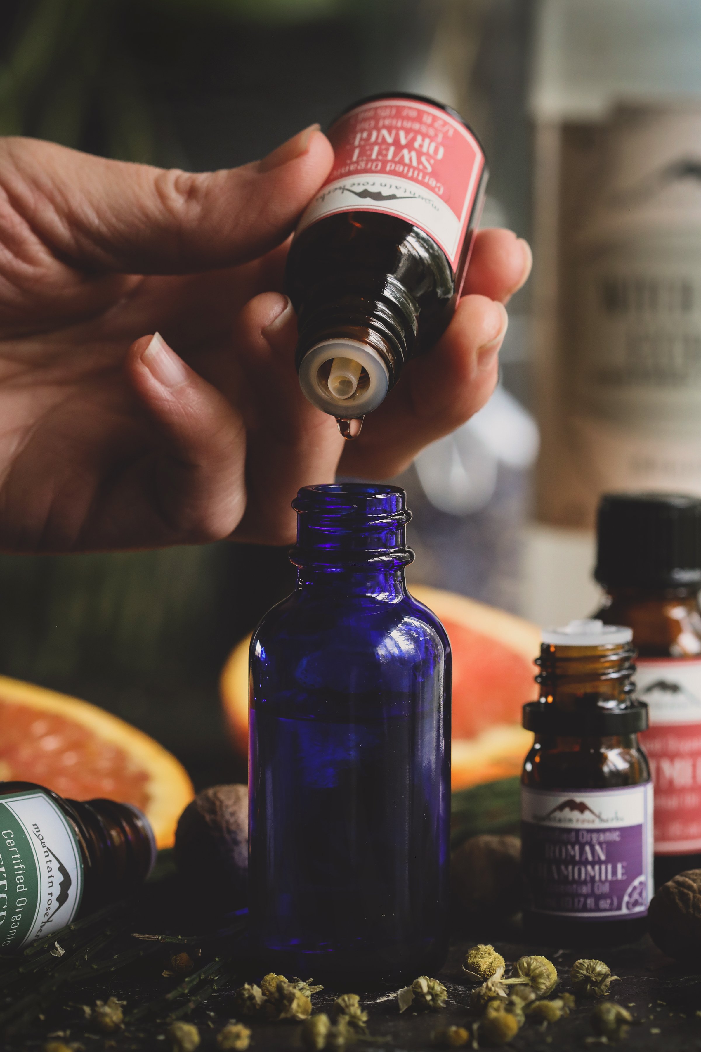 Hand dispending essential oils into pretty blue bottle. 