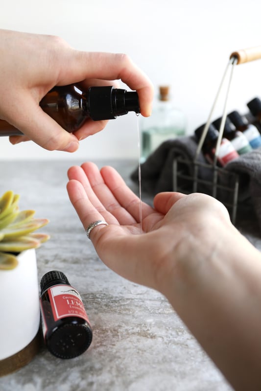 Hands applying homemade hand cleansing gel with essential oils.