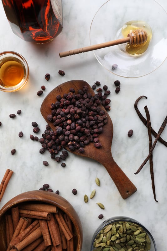 Colorful botanical ingredients displayed in wooden and glass bowls and spoons