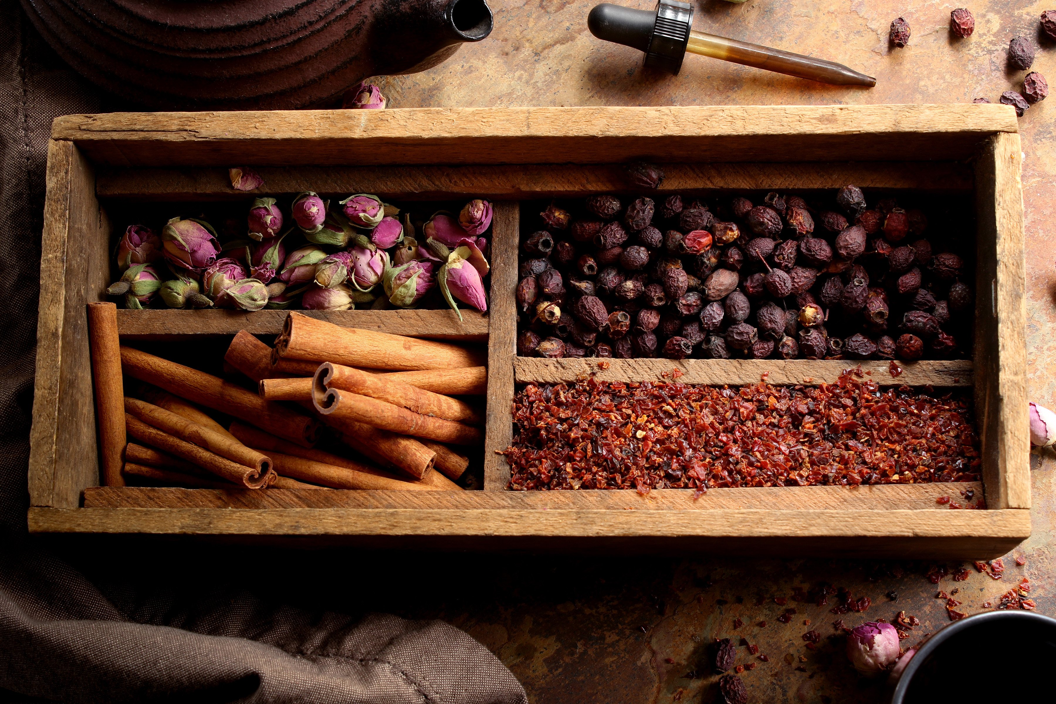 Various herbs for heartache or helping with the blues are arranged in a vintage wooden box. Herbs like rose buds, cinnamon, rosehips, and hawthorn are all helpful when tackling sadness or heartbreak. 