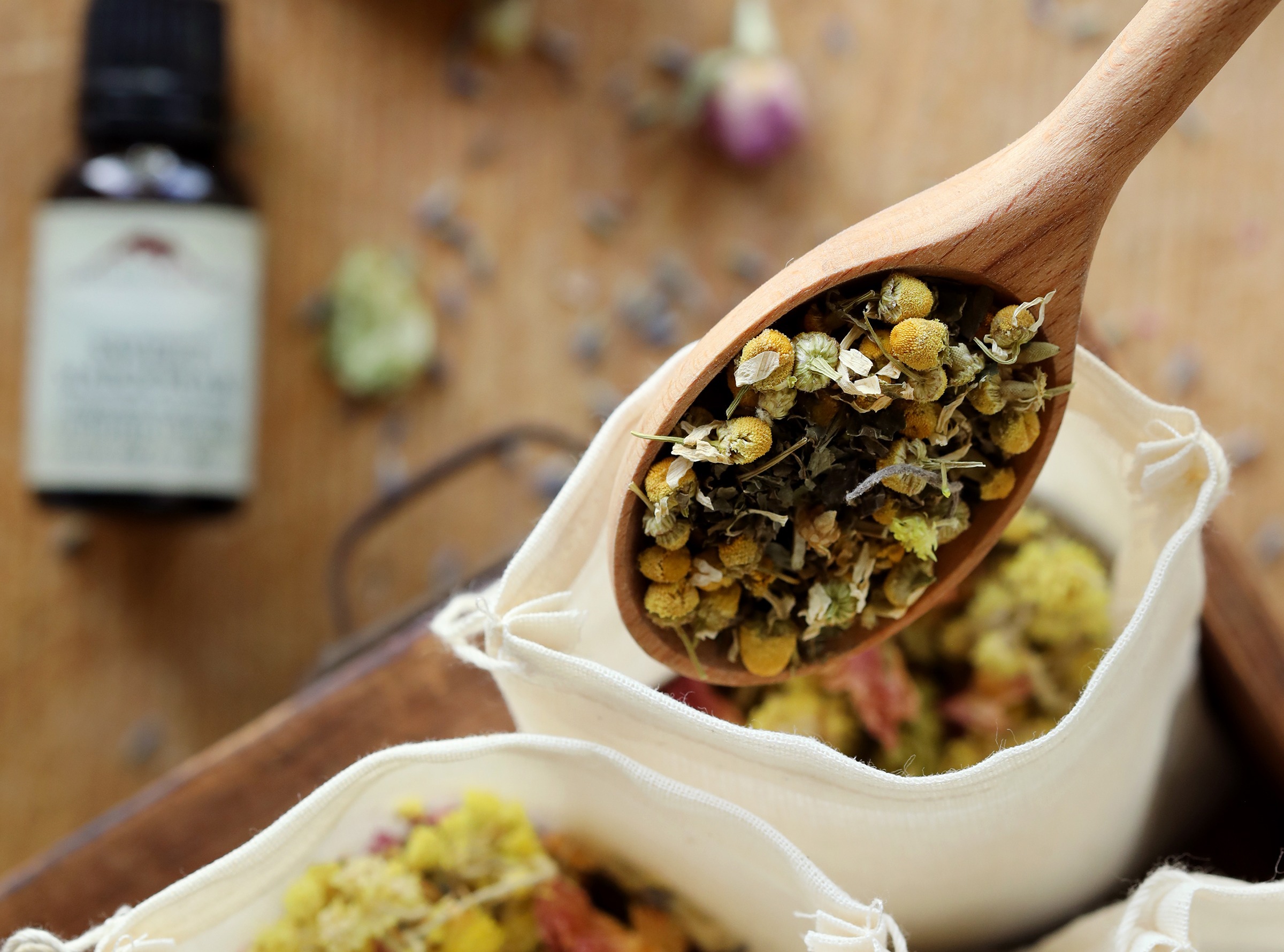 Herbs being combined together in a cotton muslin bag to create herbal dream pillows. Chamomile, rose petals, mugwort, and essential oils create a relaxing potpourri for bedtime and good dreams.  