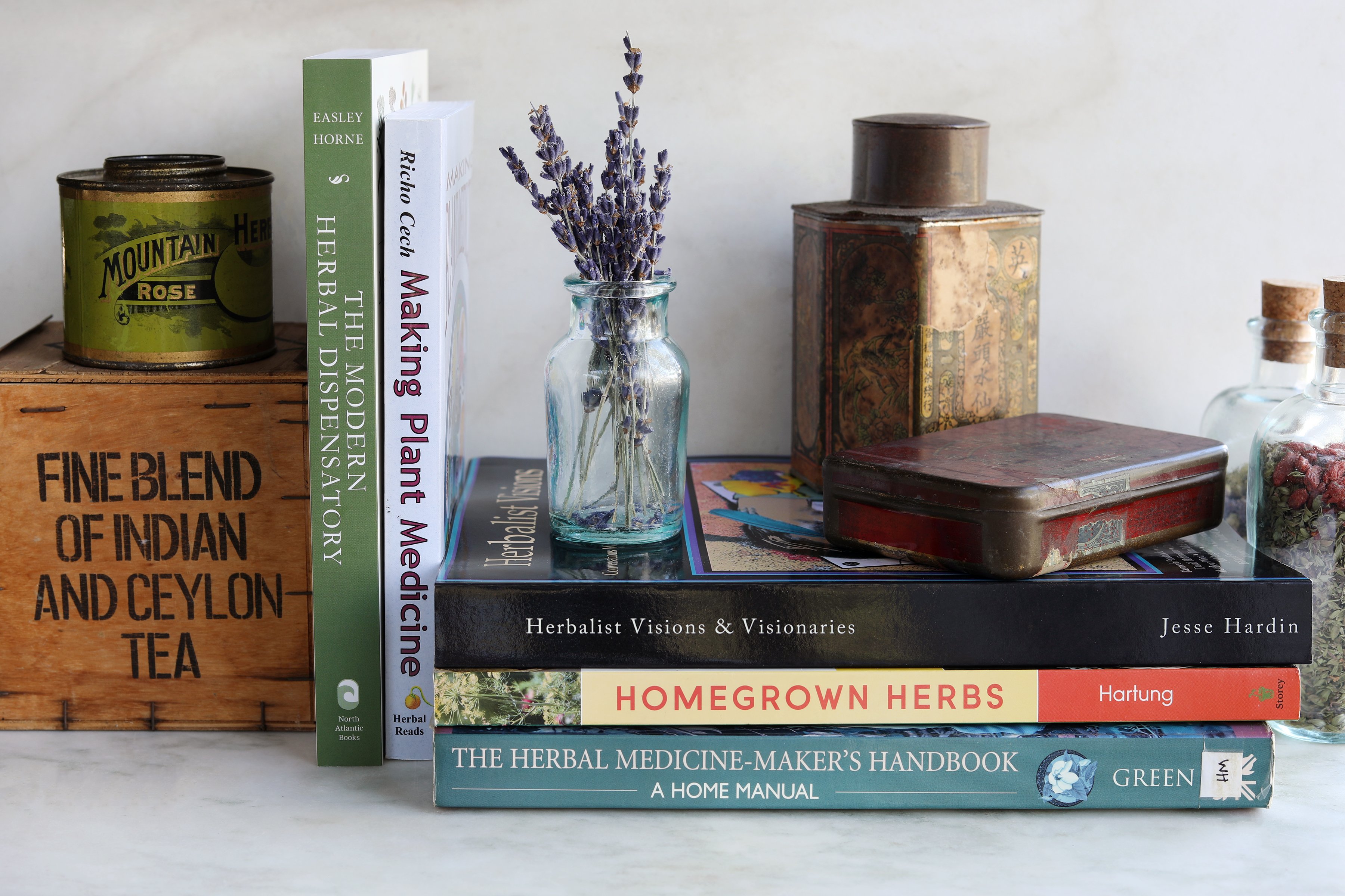 Stacks of herbal books with vintage props and fresh sprigs of lavender flowers
