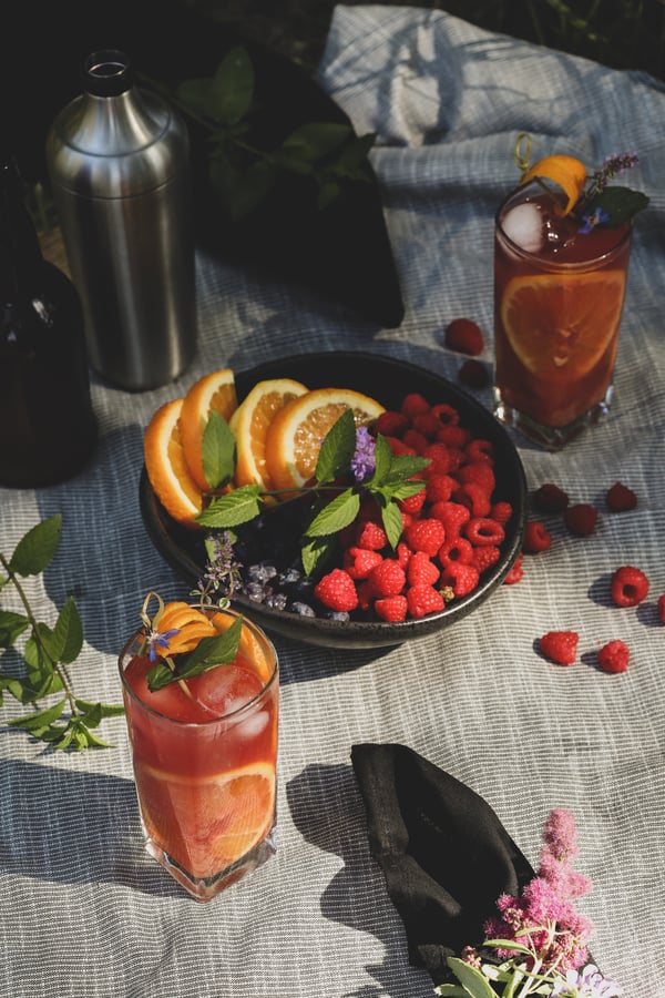 An herbal highball on a picnic blanket with fresh fruit.