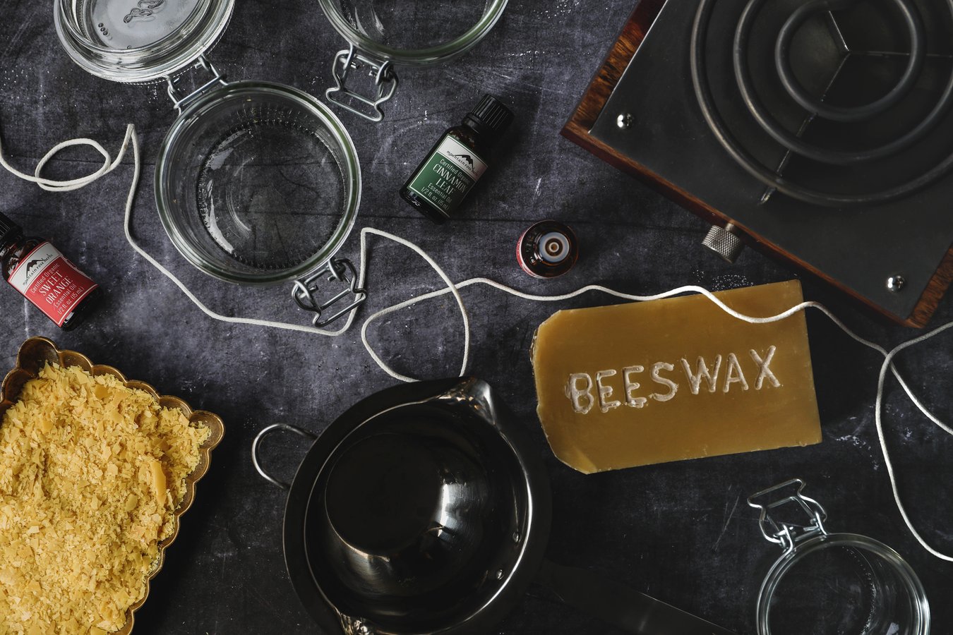 Beeswax, carnauba wax, essential oils, and other candle making supplies laid out on a table