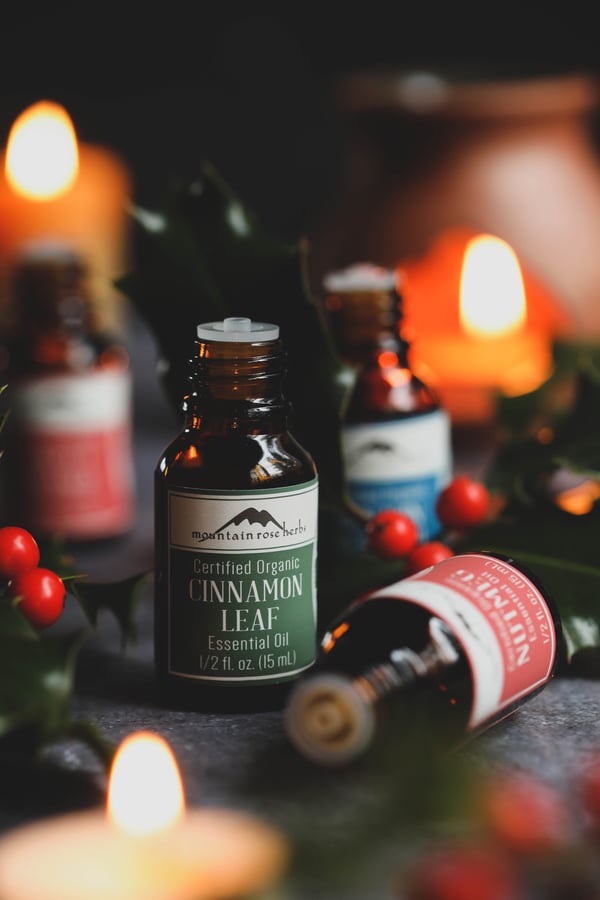 Sweet orange, cinnamon, and nutmeg essential oils in candlelight.