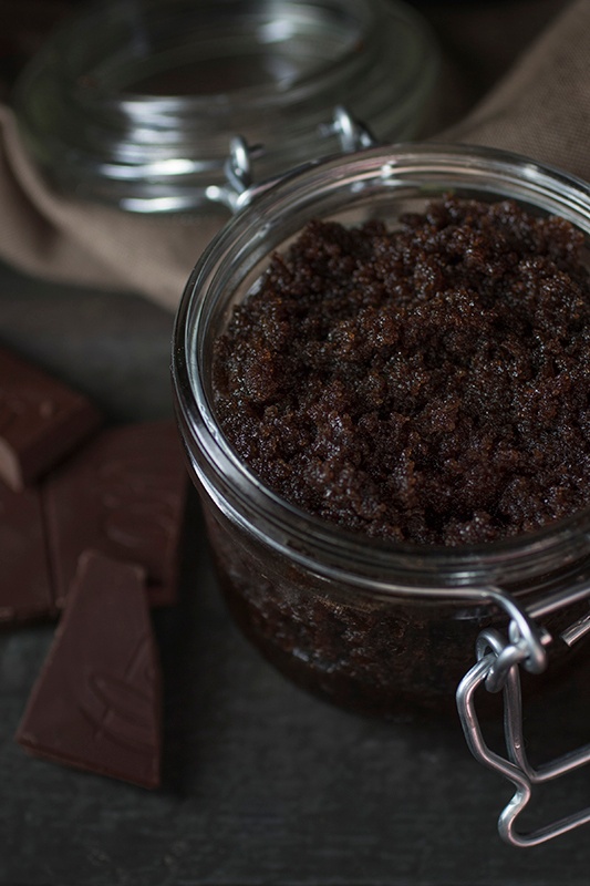 Homemade Cacao & Vanilla Body Polish in a glass jar next to raw bars of chocolate
