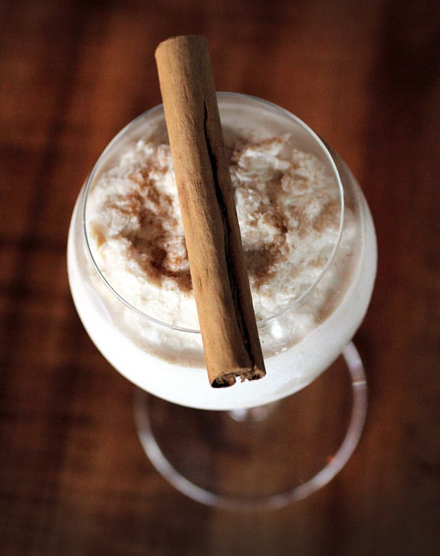 Organic cinnamon stick atop cocktail glass with Chai Snow Punch