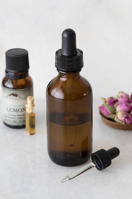 Herbal Oil in a Amber Bottle on marble tabletop with Organic Lemon Essential Oil