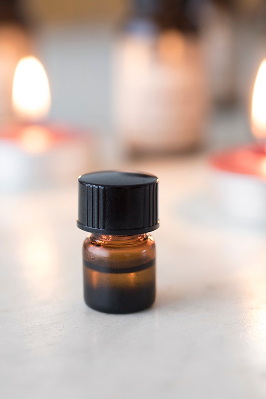 Small vial of essential oils with a warm candle light