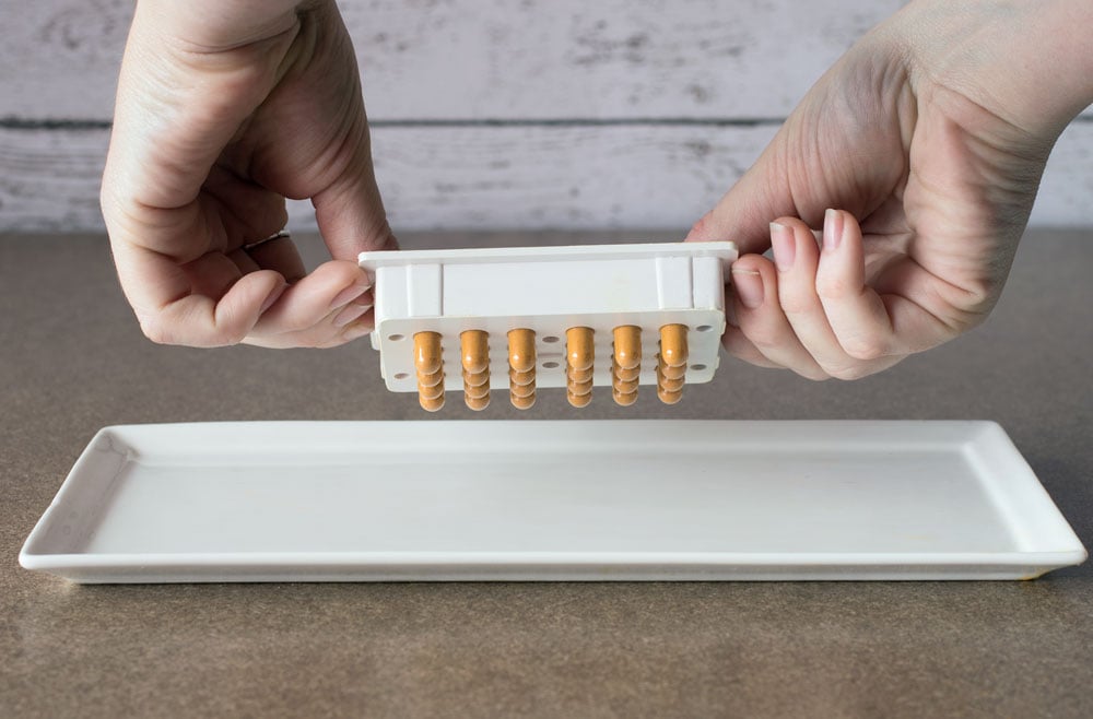 Hands popping finished DIY turmeric capsules out of the capsule machine