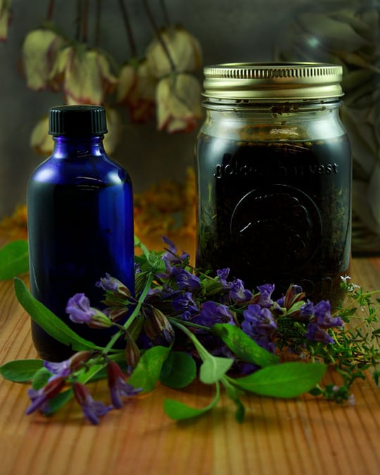Jar of herbal liniment with herbs on table 