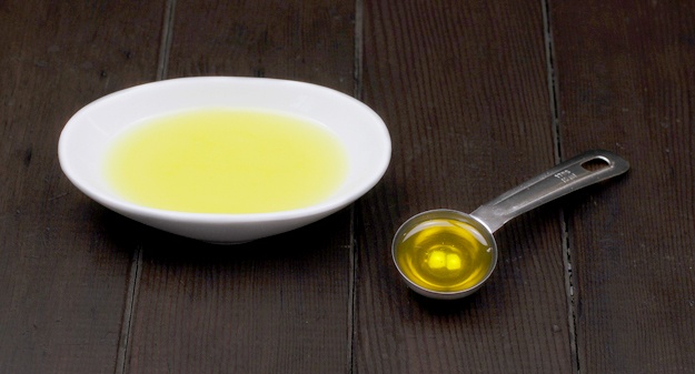 melted oils for whipped body butter recipe in bowl on table with measuring spoon