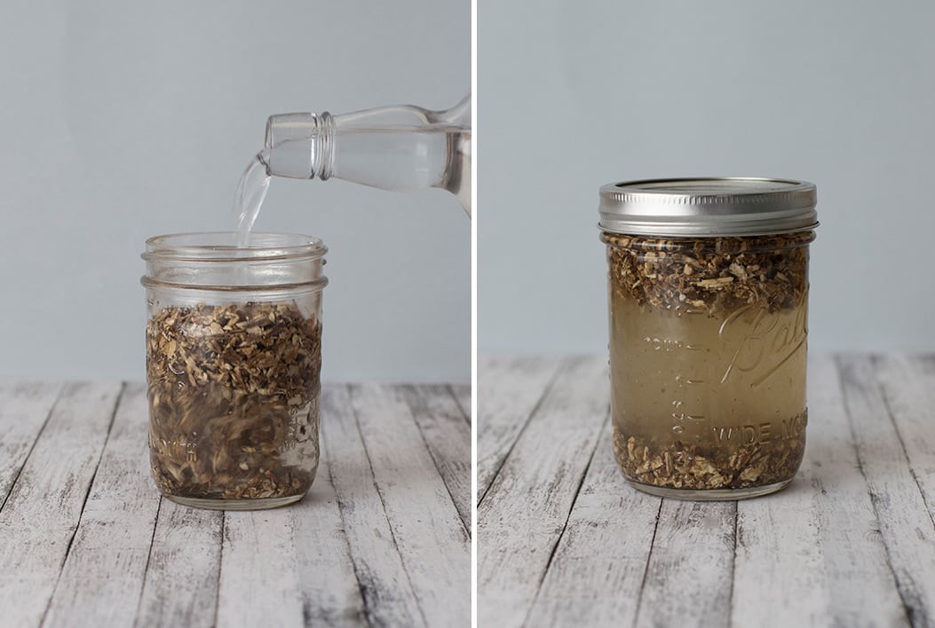 Alcohol being poured over herbs for tinctures in glass mason jars on wooden tabletops with white background.