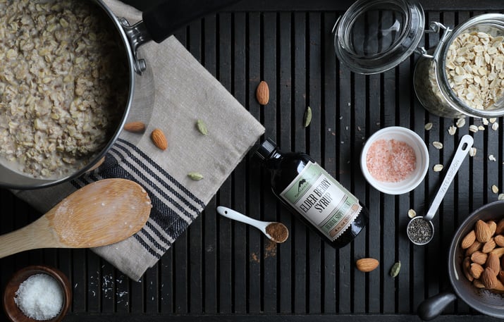 Ingredients for making overnight oats with elder berry syrup and other ingredients on table