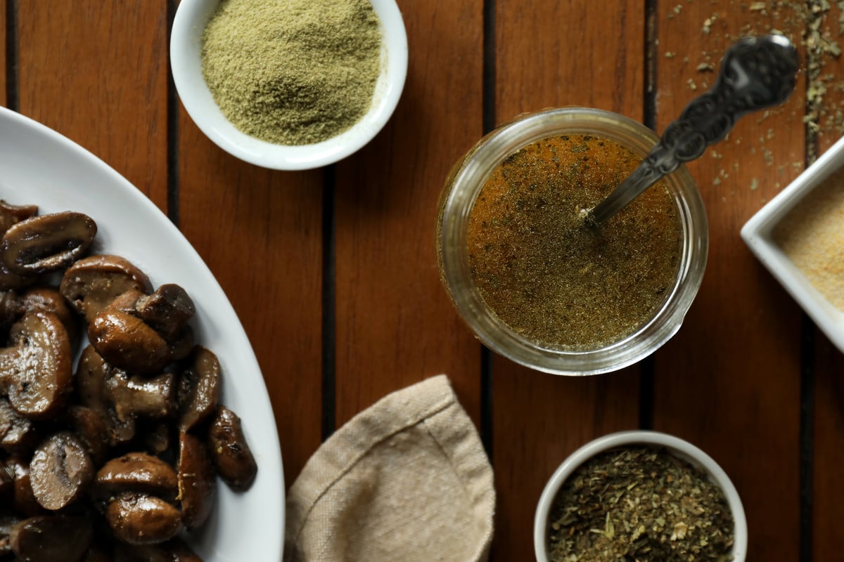 Italian herb and garlic infused ghee with bowls of organic seasonings and sauteed mushrooms.