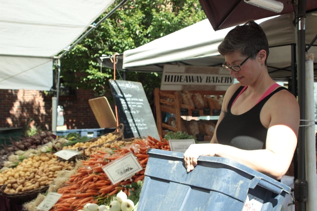 Julia, Mountain Rose Herbs Employee, working at a local farm stand at farmers market with fresh vegetables