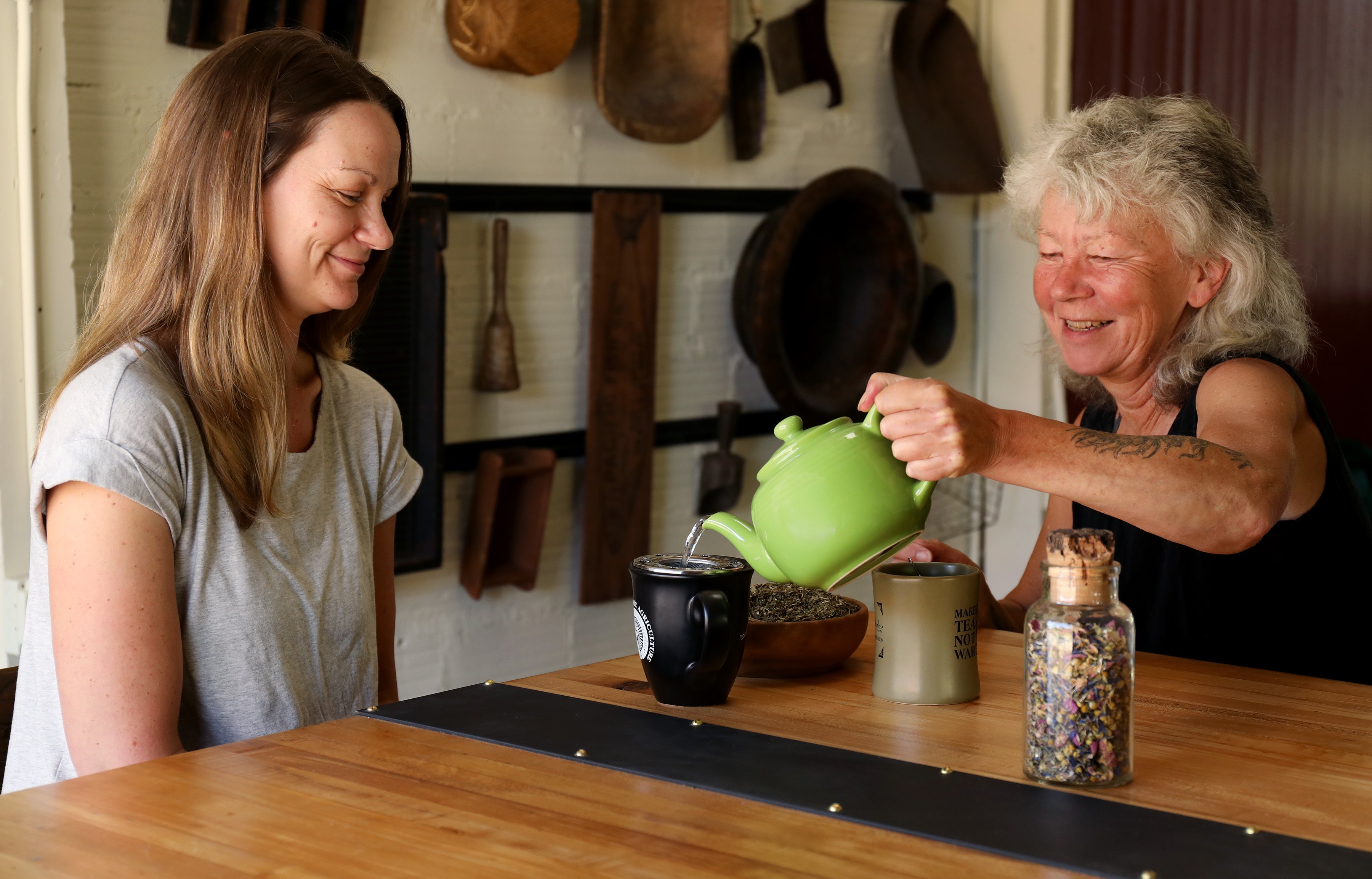 Co-owner Julie Bailey pours production manager Julie DeBord a cup of peace tea blend from Mountain Rose Herbs.