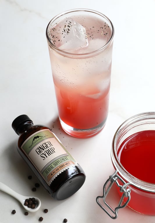 Glass with ize and crannberry drink made with herbs, spices, and ginger syrup