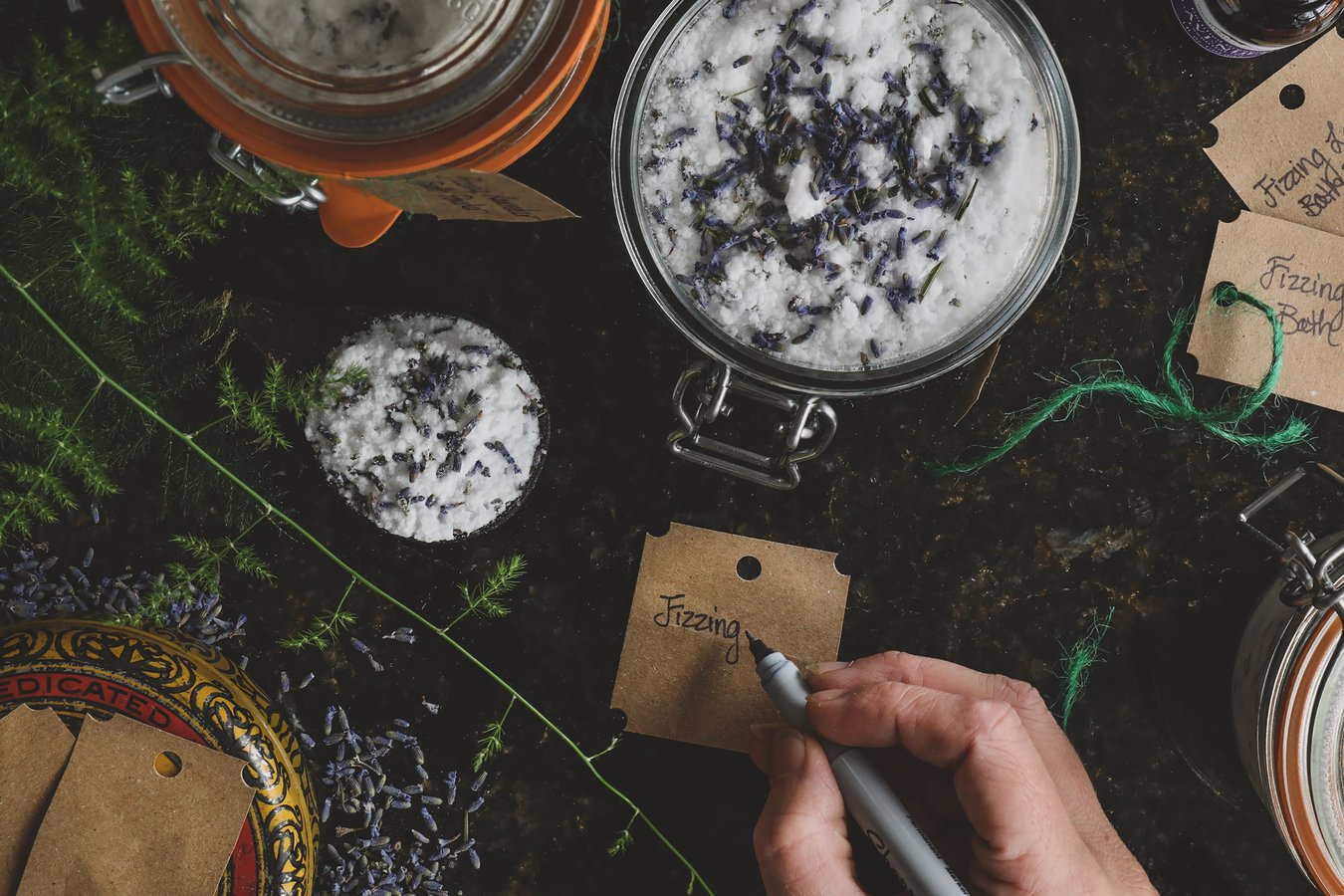 A person making labels for gift jars of homemade fizzing lavender bath powder