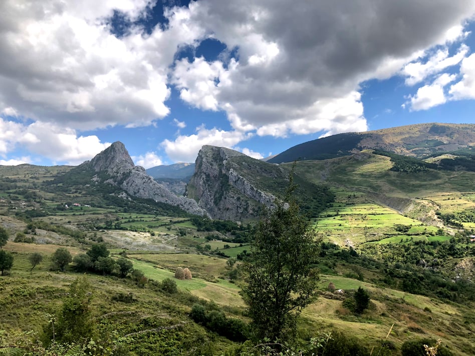 Sweeping view of the Albanian landscape in early autumn, highlighted by the sun peeking through the clouds.