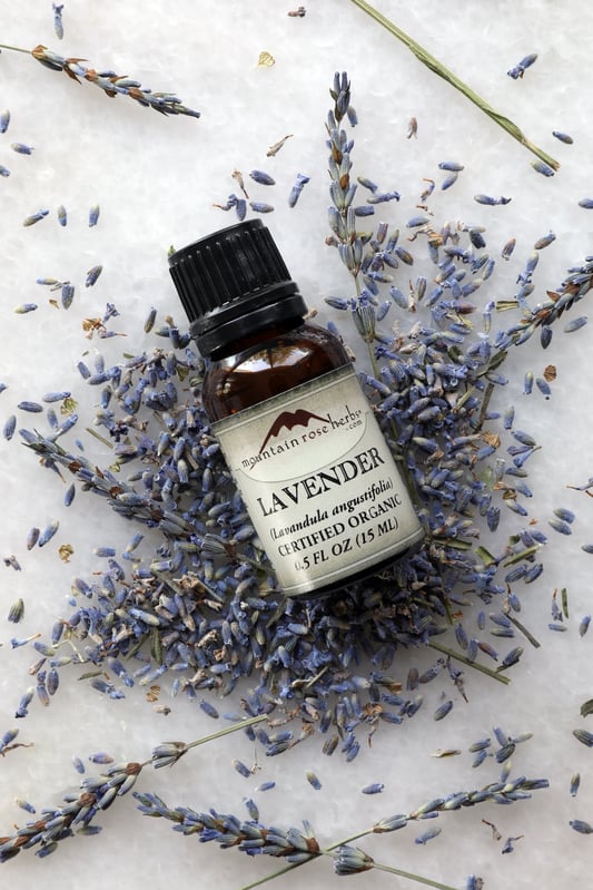 1/2 oz. bottle of lavender essential oil laying on dried lavender flowers