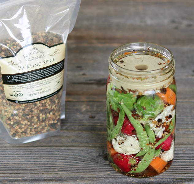 Mason jar filled with fermented veggies and pickling spice and Mountain Rose Herbs pickling spice