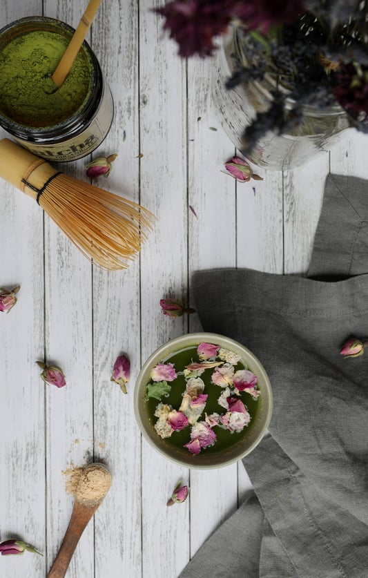 Mug with Matcha Tea and rose petals with tea accessories and cloth