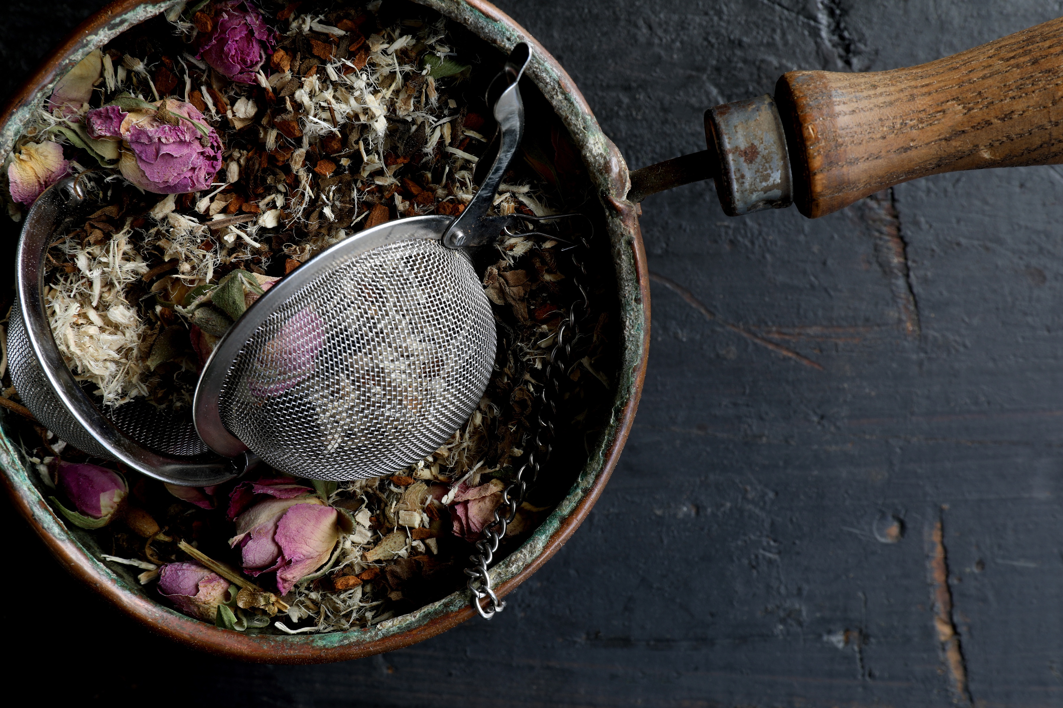 Hand-blended marshmallow rose tea in basket tea strainer with wooden handle