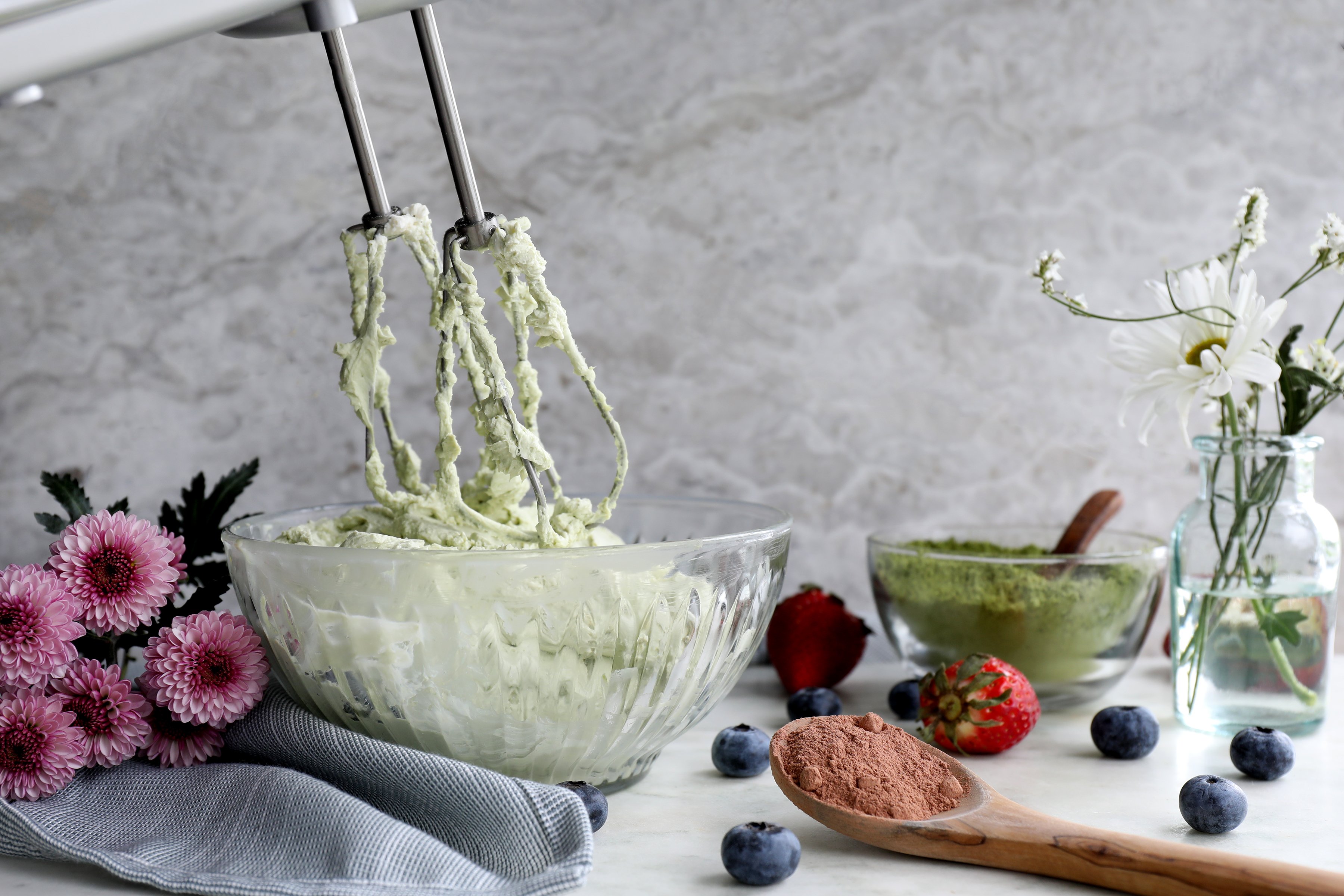 Matcha cheesecake filling in whipped with ingredients in the background.