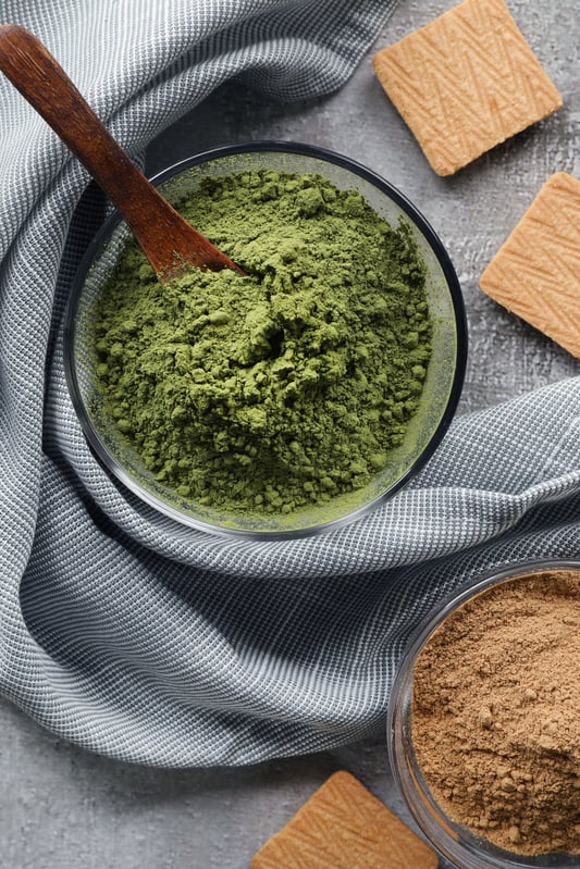 A glass bowl with bright green matcha powder and crumbled shortbread cookies