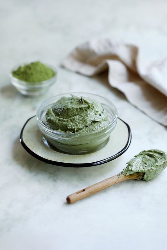 Vibrant green matcha tea powder is combined with clay and coconut to create a green tea face mask for skin care. 
