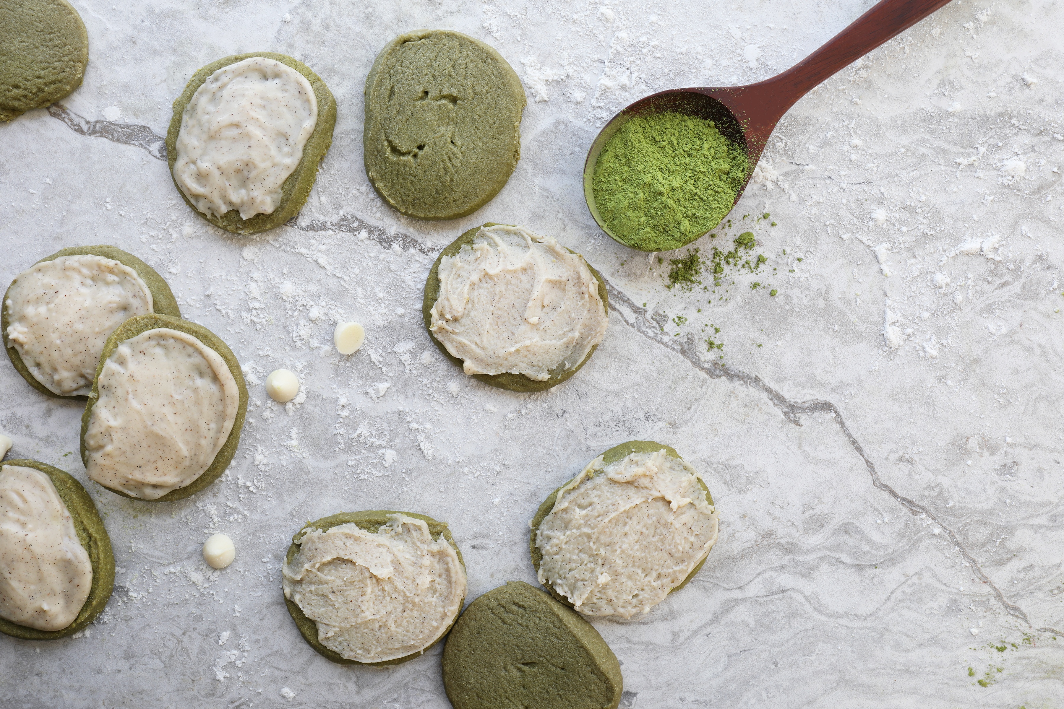 Matcha shortbread cookies sitting on granite counter with spoon of matcha powder and white chocolate chips