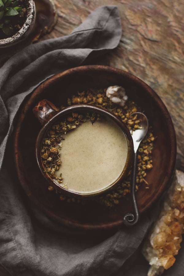 Mug of hot drink with chamomile and decorative spoon. 