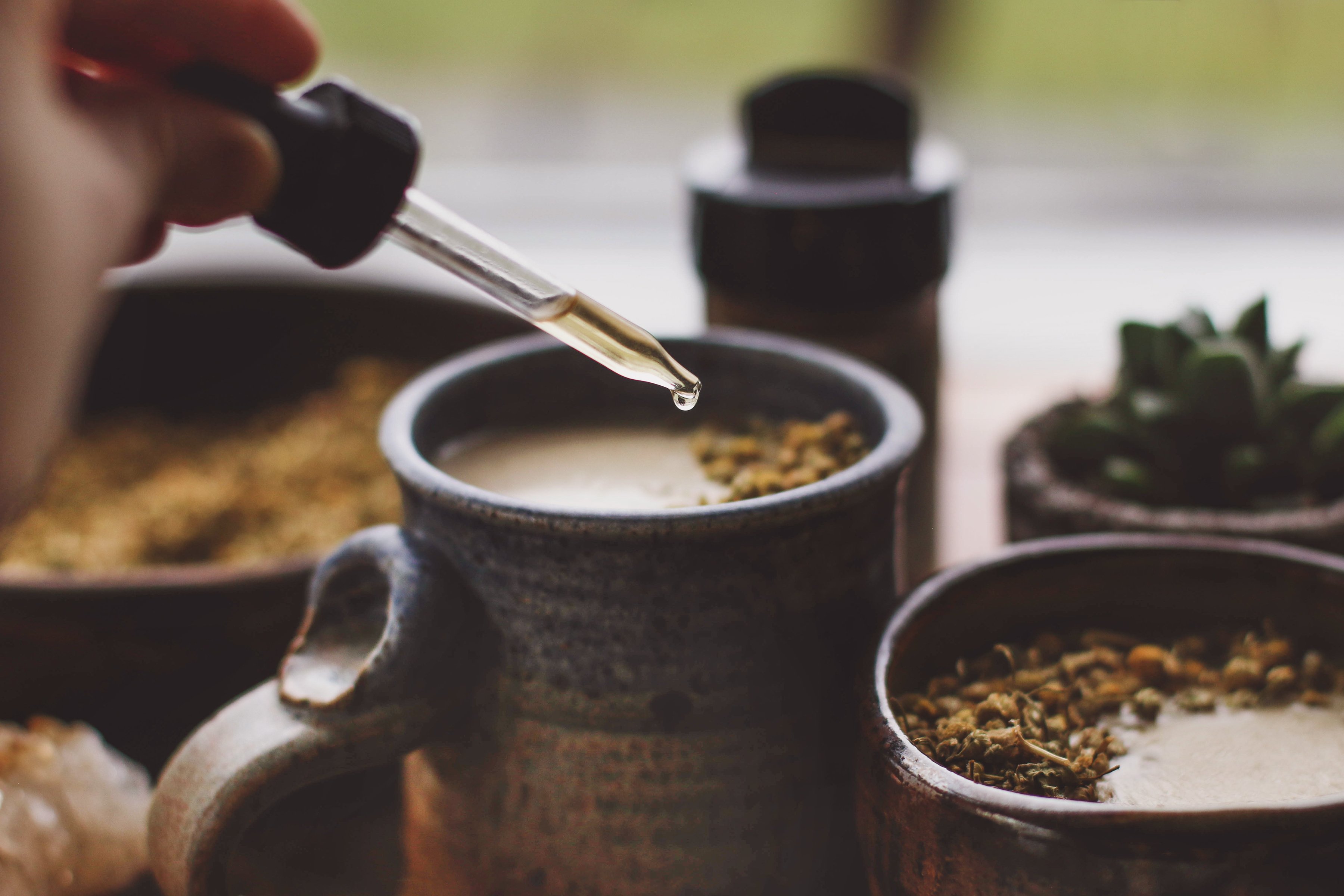 Hand dropping tincture into hot beverage. 